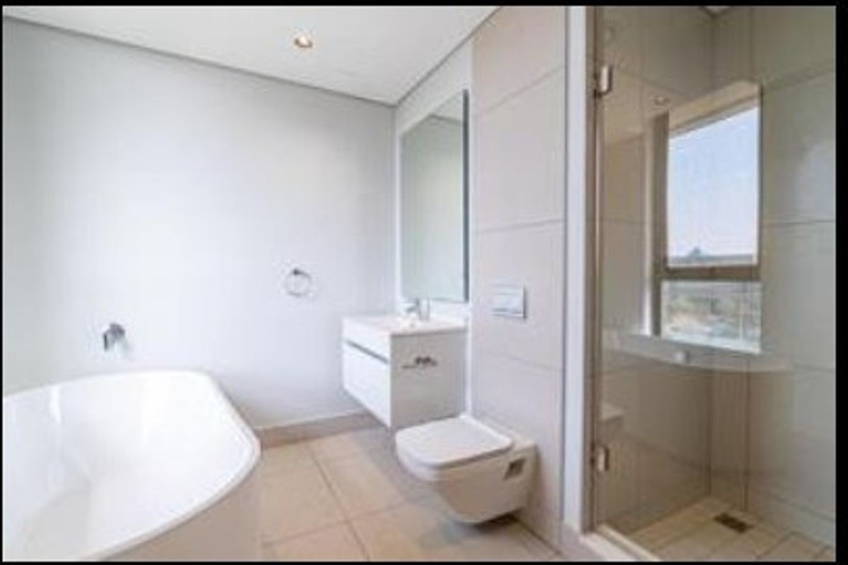 Modern bathroom featuring a sleek freestanding bathtub, wall-mounted vanity, wall-hung toilet, and a glass-enclosed shower with contemporary tile finishes.