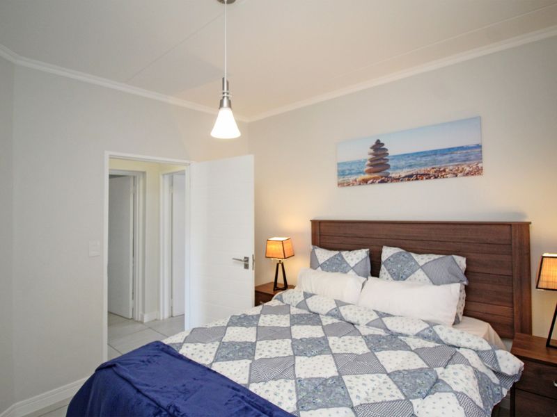 A well-maintained bedroom featuring neutral wall finishes, coving, and a modern pendant light fixture.