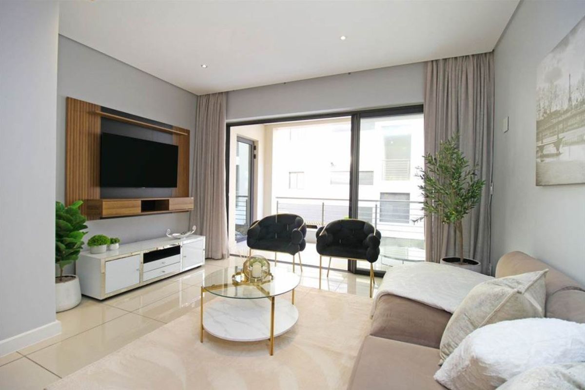 Modern living room featuring tiled flooring, recessed lighting, and large sliding glass doors leading to a balcony, with a built-in media unit.