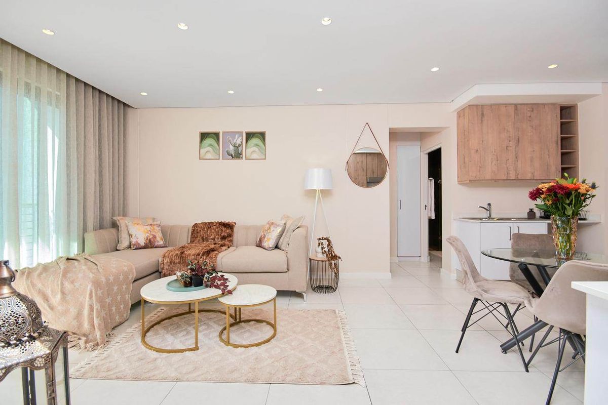 Modern open-plan living area featuring tiled floors, recessed lighting, and a compact kitchen corner with built-in cabinetry and sink.