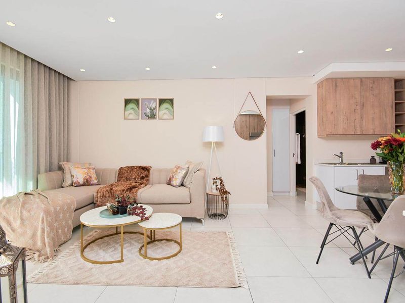 Modern open-plan living area featuring tiled floors, recessed lighting, and a compact kitchen corner with built-in cabinetry and sink.