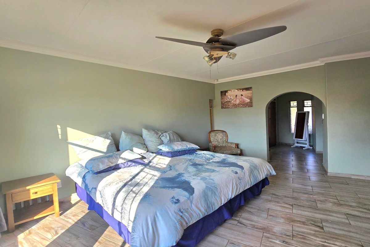 Spacious bedroom featuring tiled flooring, a ceiling fan, and an arched entryway leading to an adjoining space.