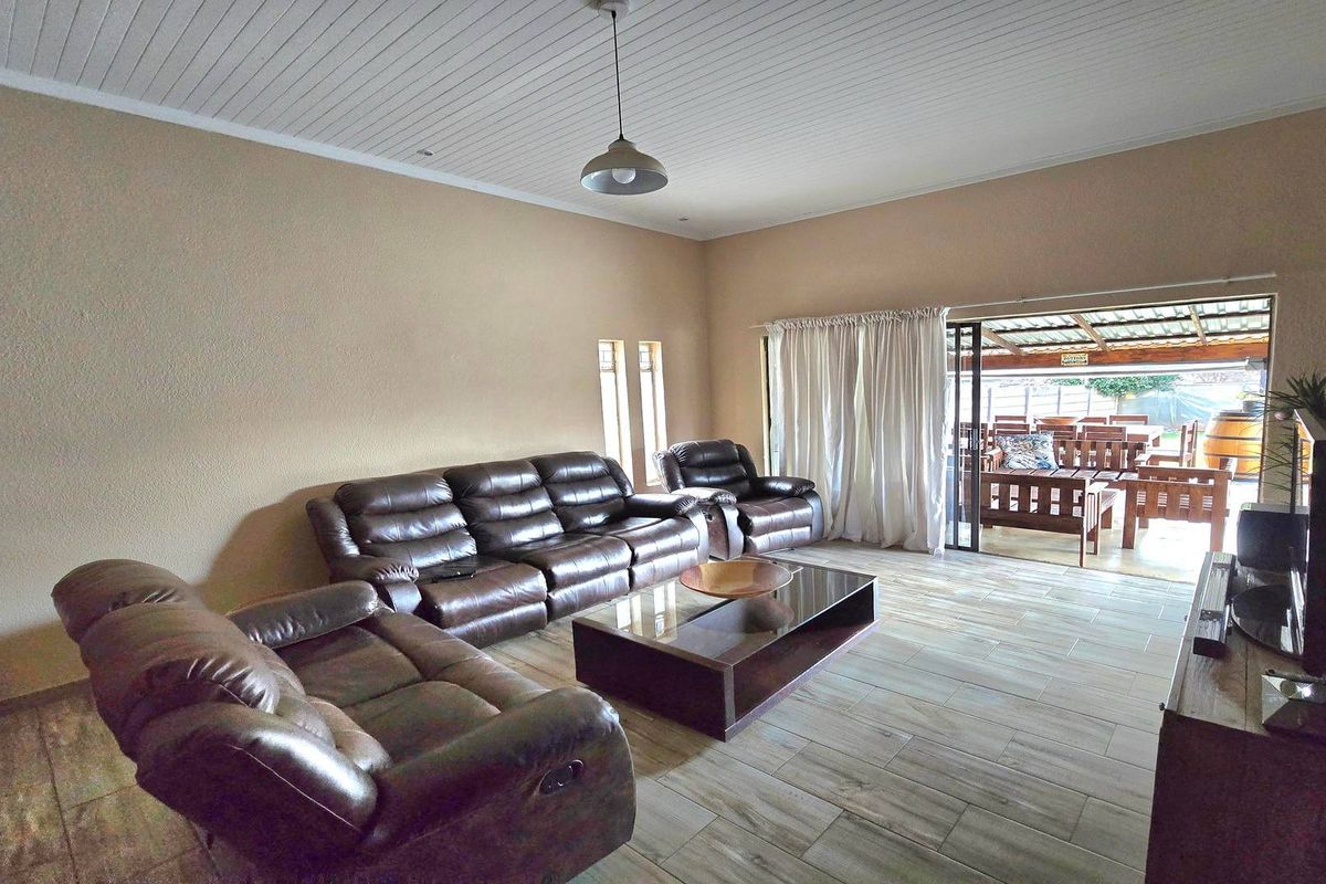 Spacious living room featuring tiled flooring, a tongue and groove ceiling, and a large sliding glass door providing access to the outdoor patio area.