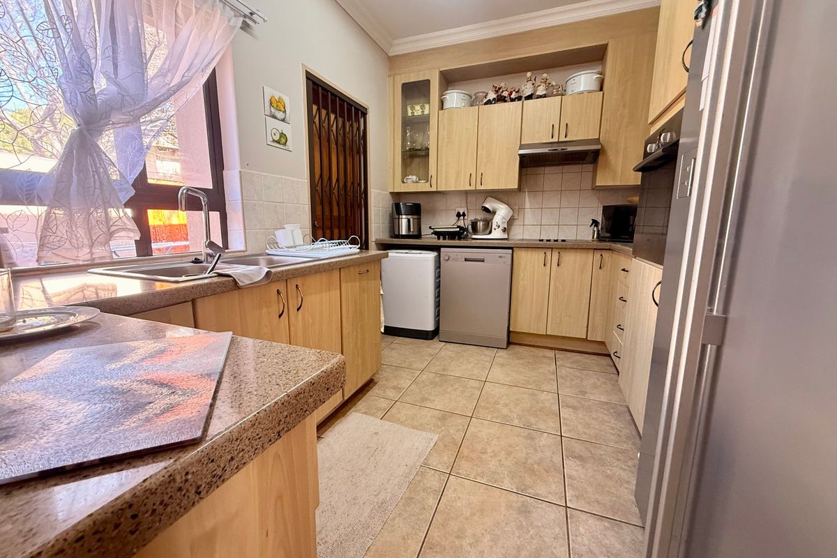 Functional kitchen featuring light wood cabinetry, granite countertops, tiled flooring, and integrated appliances, offering a practical layout for daily meal preparation.