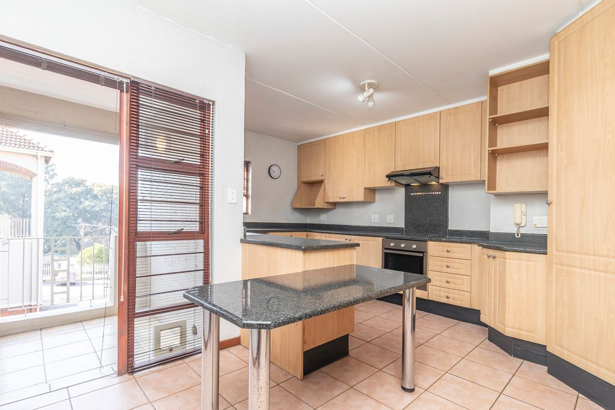 A functional kitchen featuring light wood cabinetry, granite countertops, built-in oven, and direct access to an outdoor balcony area.