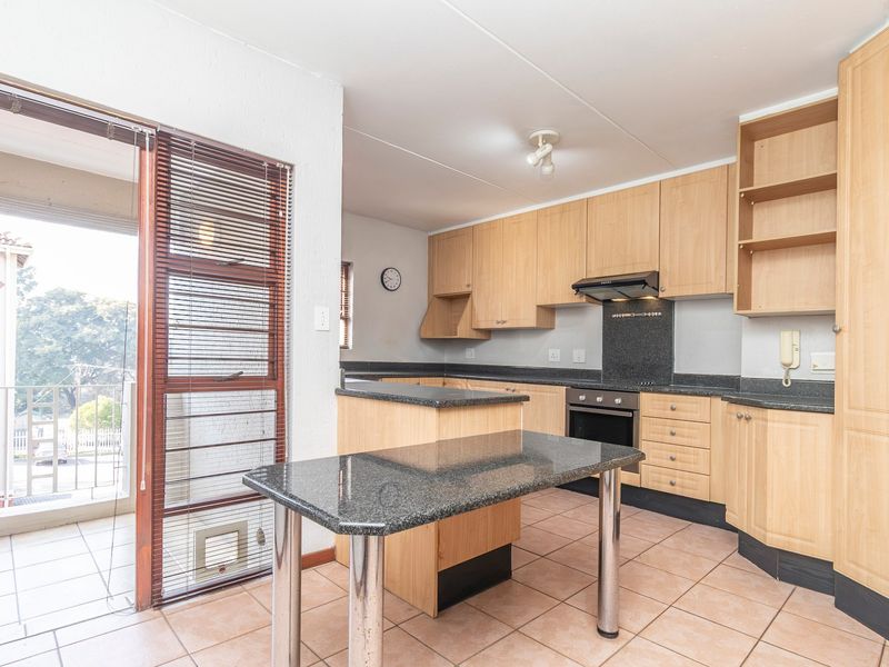 A functional kitchen featuring light wood cabinetry, granite countertops, built-in oven, and direct access to an outdoor balcony area.