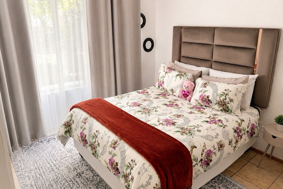 A well-maintained bedroom featuring tiled flooring and large windows with curtain tracks, providing a bright and comfortable living space.
