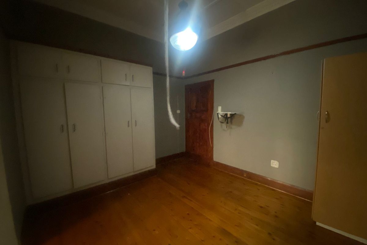A vacant bedroom featuring original timber flooring, built-in cupboards, and classic architectural details like picture rails and coved ceilings, requiring minor cosmetic updates.