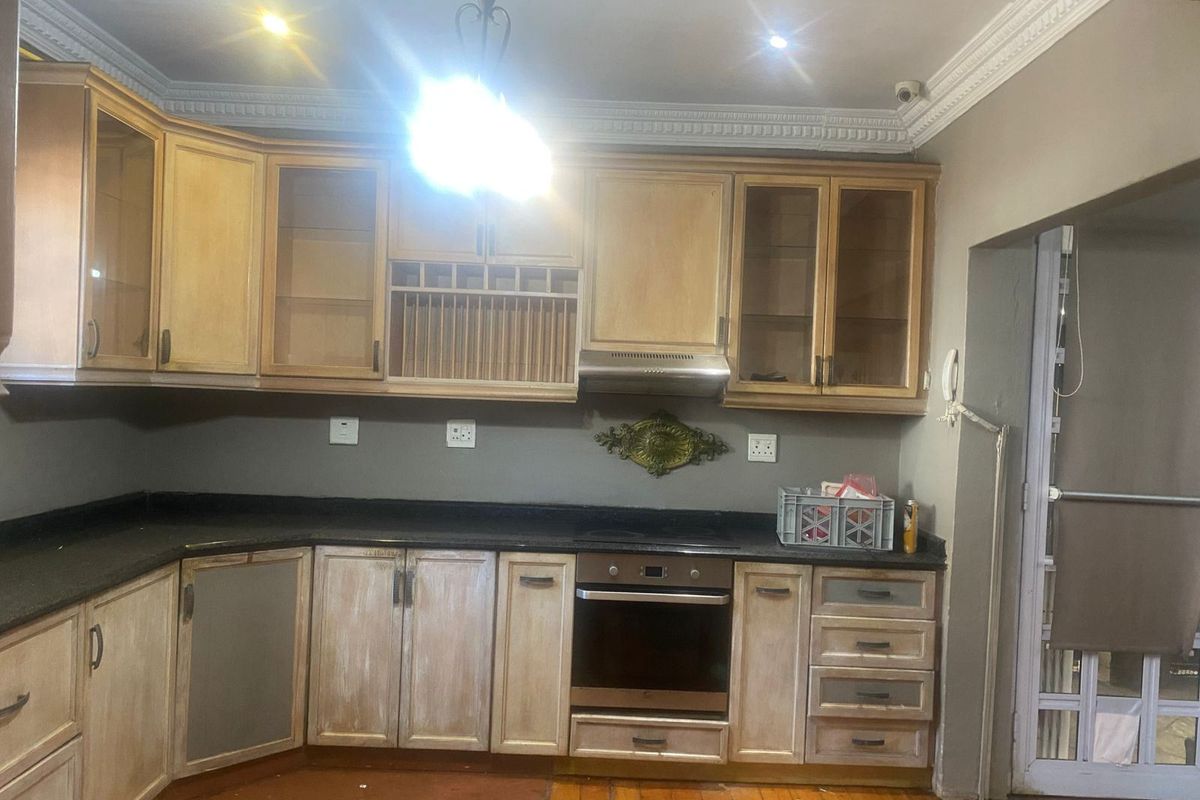 A functional kitchen featuring wooden cabinetry, black granite countertops, built-in oven, extractor fan, and classic crown molding details.