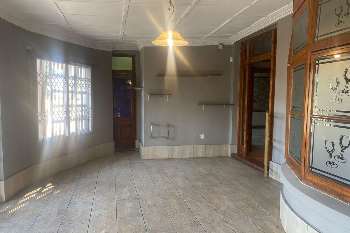 An empty living area featuring tiled flooring, decorative ceiling details, and built-in wall shelving, offering a neutral canvas for potential interior design updates.