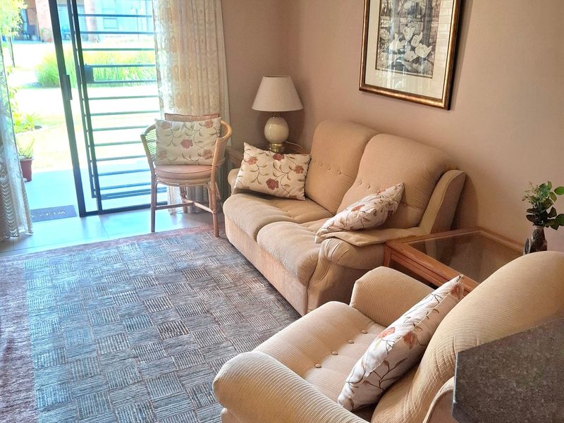 A comfortable living room featuring tiled flooring and a sliding glass door with security gate providing access to the outdoor area.