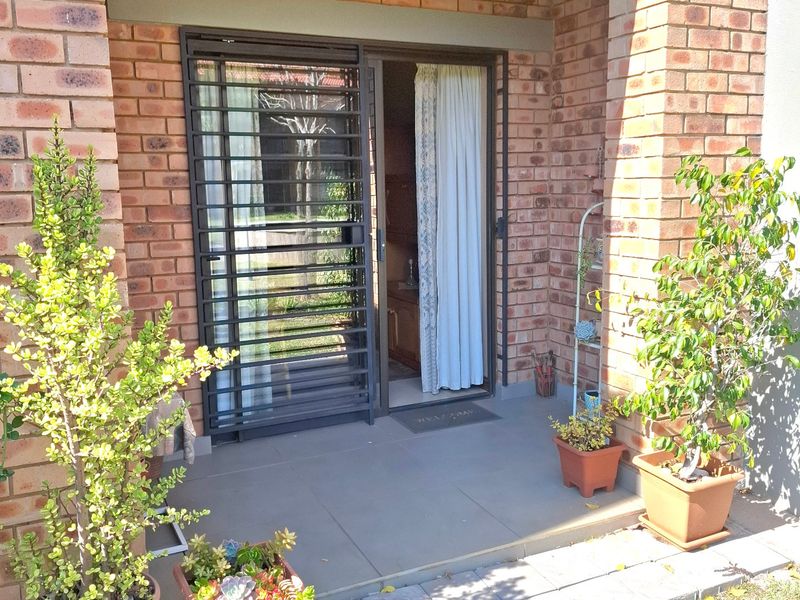 A covered patio area featuring brick pillars, tiled flooring, and a secure sliding door entrance.