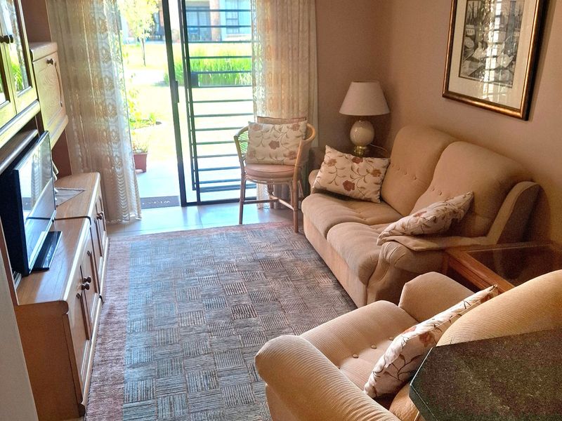 A cozy living room featuring tiled flooring, a sliding glass door with security gate, and direct access to an outdoor area.