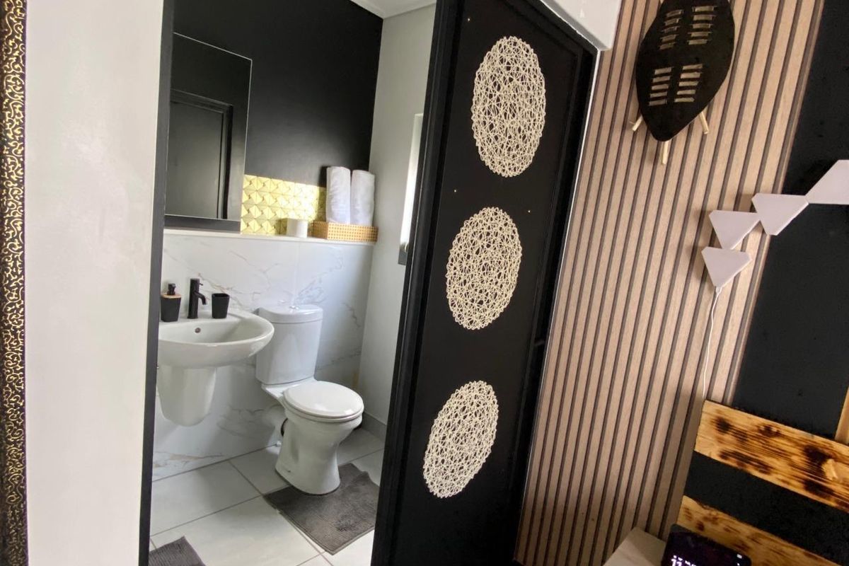 A modern bathroom featuring a pedestal basin and toilet, accessed via a sliding door from the adjacent bedroom area.