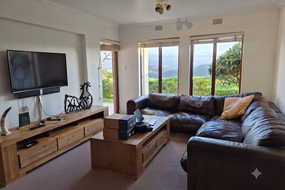 Spacious living room featuring large windows and sliding glass doors that provide natural light and scenic views of the surrounding landscape.