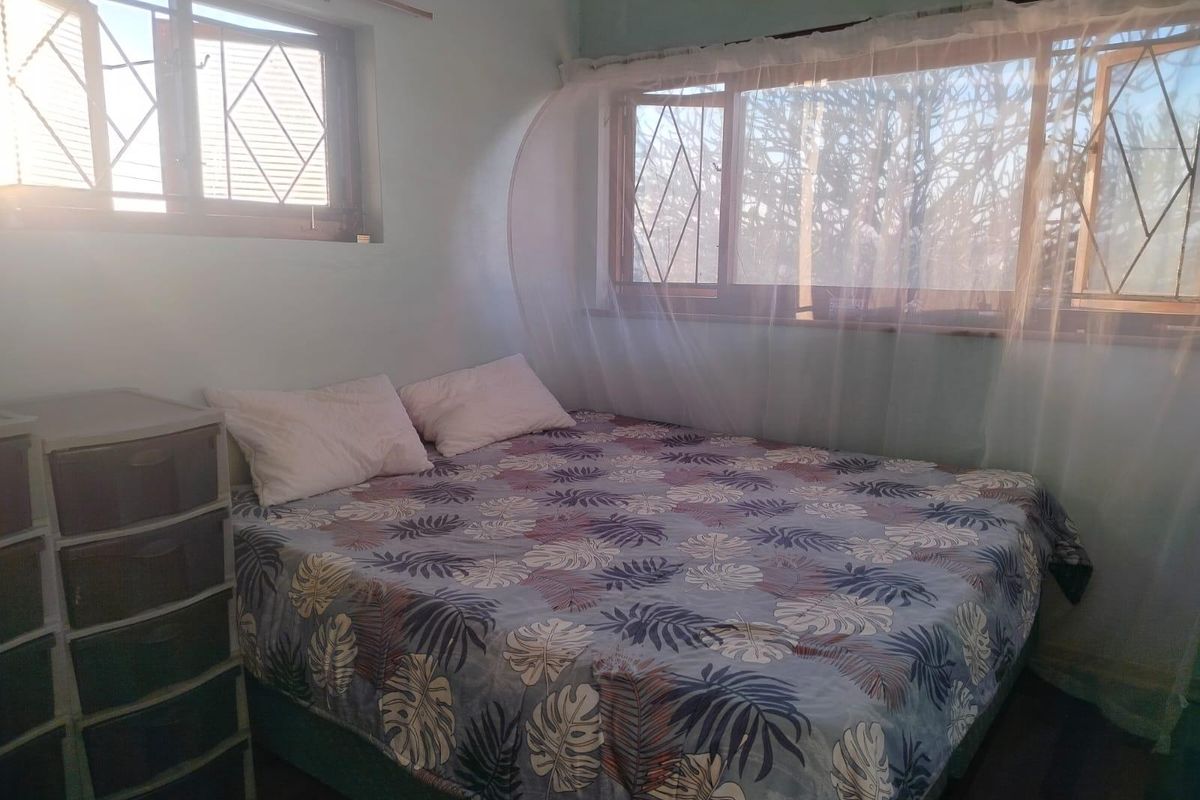 A functional bedroom featuring natural light through casement windows with integrated security bars.