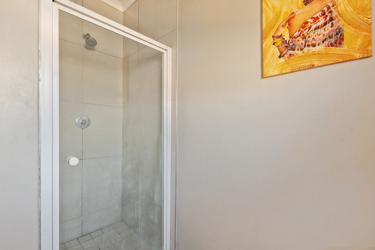 A functional bathroom featuring a glass-enclosed shower with neutral wall tiling and a standard shower fixture.