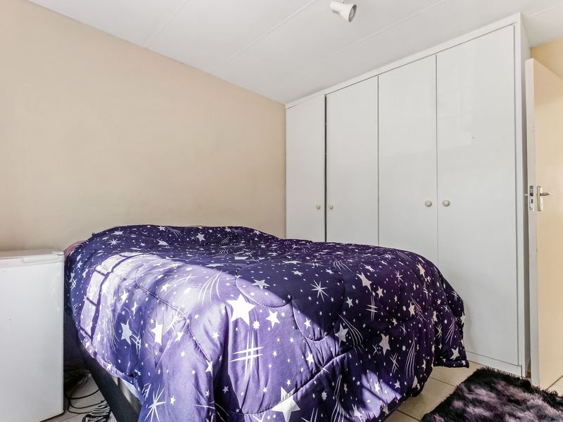 A functional bedroom featuring built-in wardrobes and tiled flooring, providing practical storage and a neutral base for interior design.