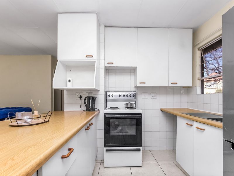 A functional kitchen featuring white cabinetry, laminate countertops, a tiled backsplash, and a freestanding stove, offering a clean and practical workspace.