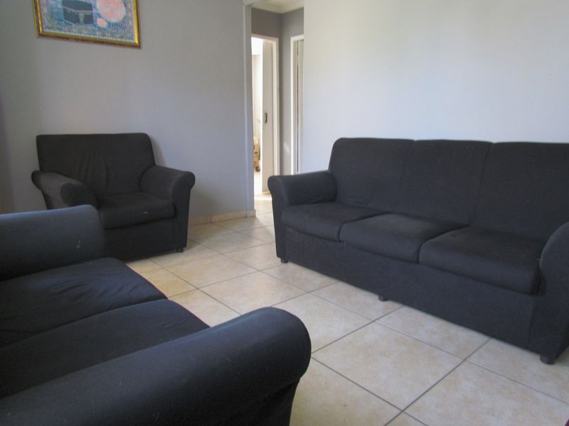 A living room area featuring neutral wall paint and ceramic floor tiles, providing a functional space for relaxation.