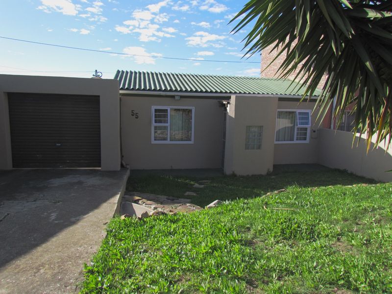 Front elevation of a cluster home featuring a single garage, corrugated metal roof, and a small front garden area.