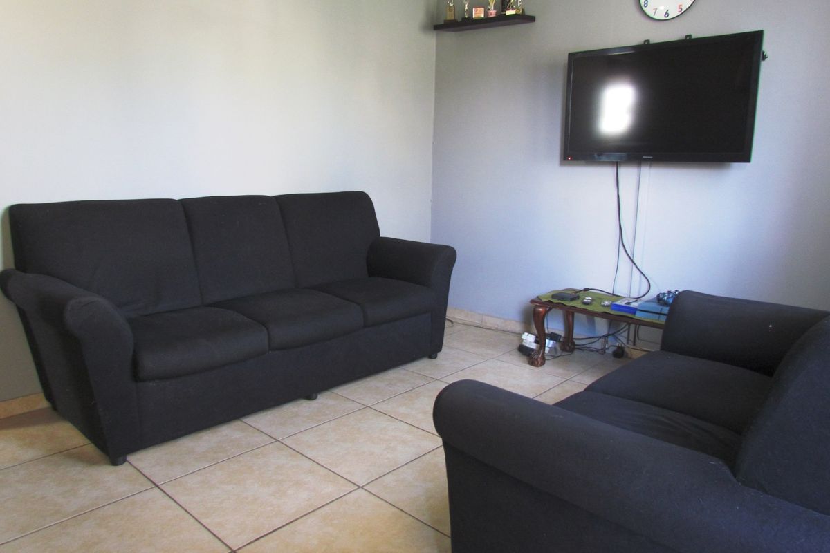 A living room area featuring neutral wall paint and tiled flooring, providing a functional space for relaxation.