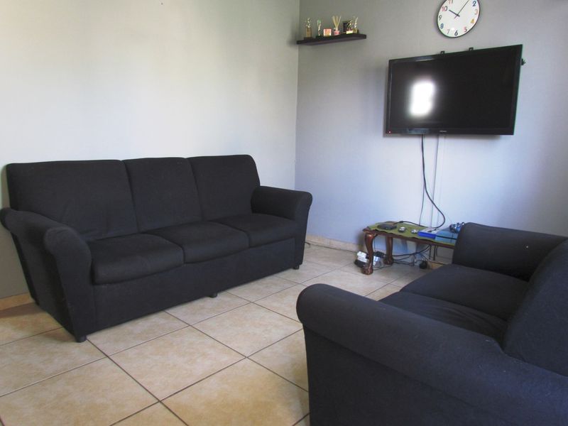 A living room area featuring neutral wall paint and tiled flooring, providing a functional space for relaxation.