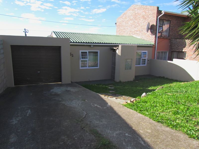 Front elevation of a cluster home featuring a single garage, concrete driveway, and a small front garden area.