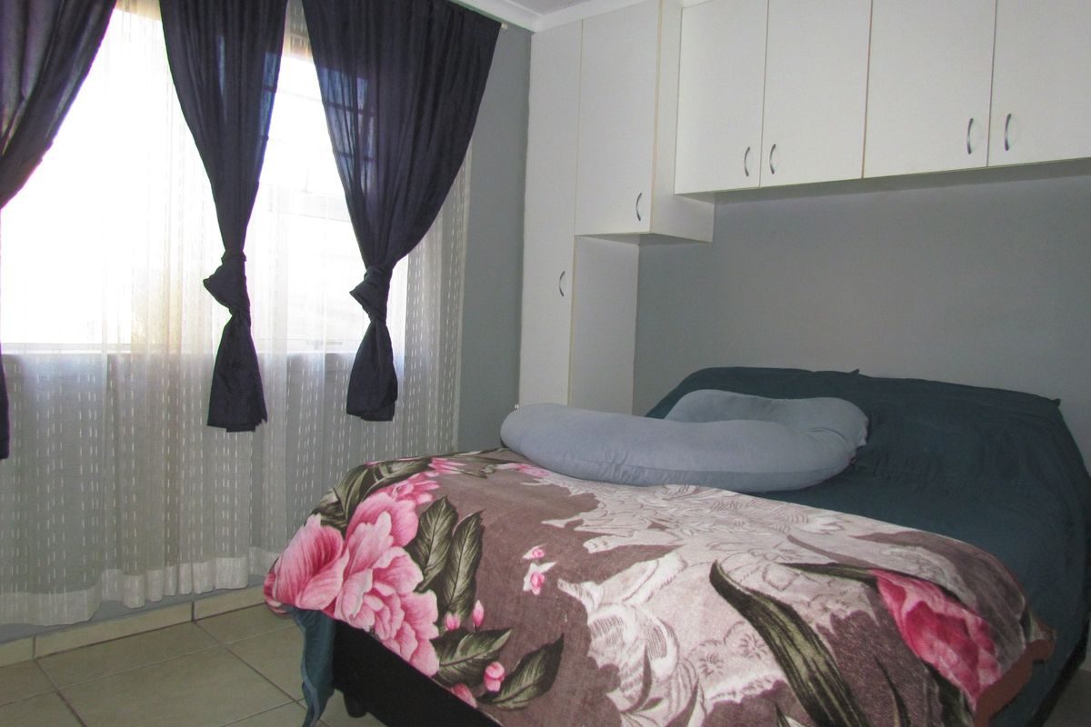 A bedroom featuring built-in cupboards and tiled flooring, providing functional storage space.