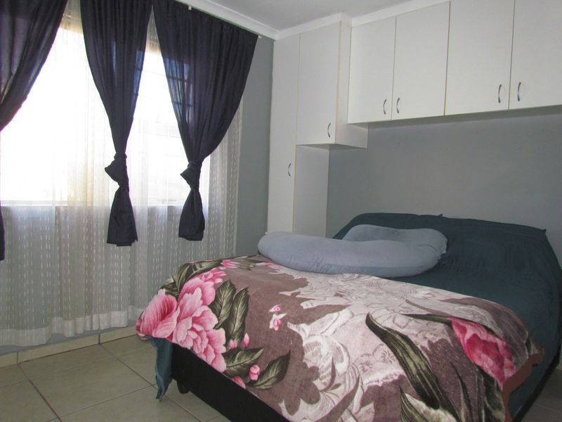 A bedroom featuring built-in cupboards and tiled flooring, providing functional storage space.