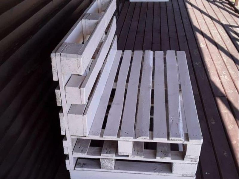 A wooden balcony or patio area featuring timber decking and log cabin style wall cladding.