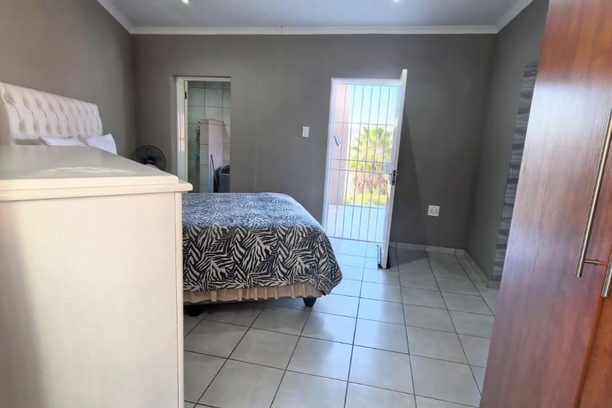 A bedroom featuring tiled flooring, recessed downlights, and a security gate leading to an outdoor area.