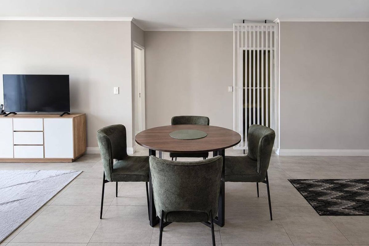 A bright and modern living area featuring neutral wall tones, large format floor tiles, and a stylish vertical slatted room divider.
