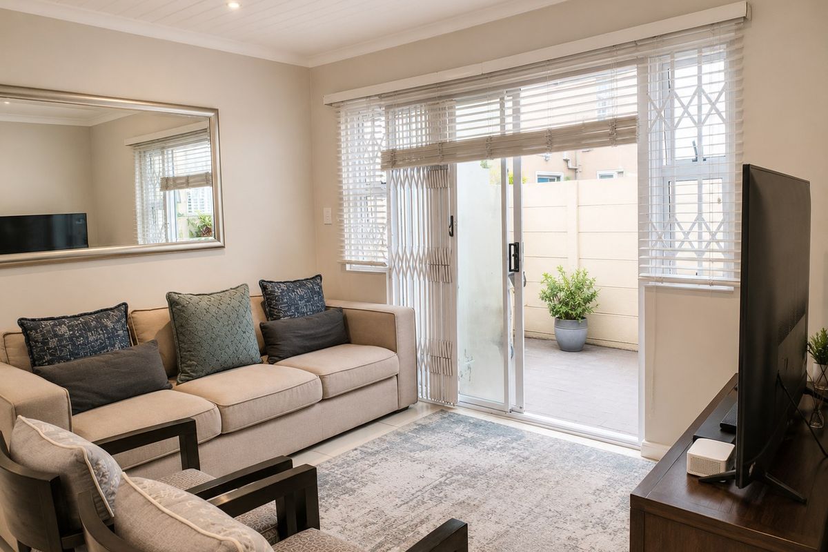 A well-maintained living room featuring a sliding glass door with security gate, venetian blinds, and a classic tongue and groove ceiling.