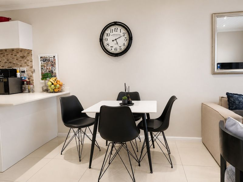 An open-plan living and dining area featuring tiled floors, a modern kitchen with stone countertops, and a mosaic tile backsplash.