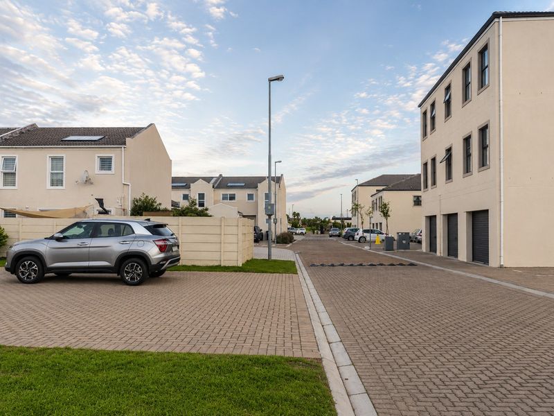 A view of the residential complex street featuring paved driveways, garage access, and well-maintained exterior building facades.