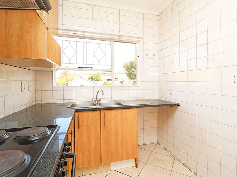 A functional kitchen featuring laminate cabinetry, granite countertops, a double basin sink, and an electric hob with an extractor fan.