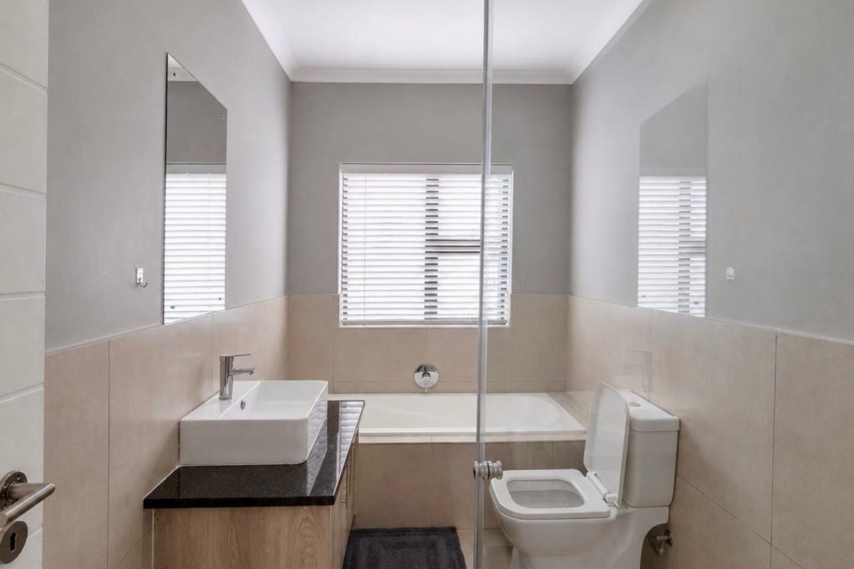 A modern bathroom featuring a vanity with granite countertop, vessel sink, built-in bathtub, and a glass-enclosed shower area.
