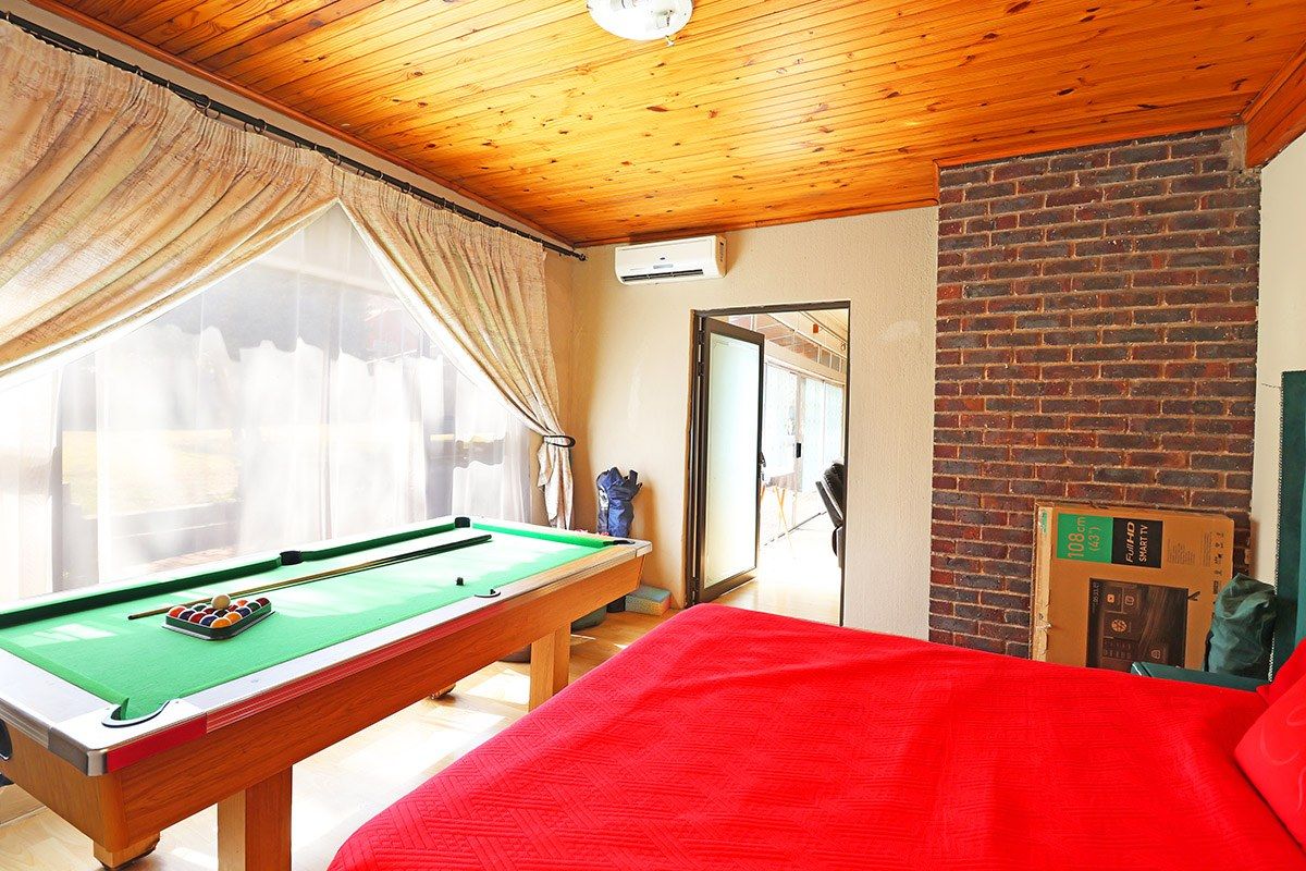 A living area featuring a timber-clad ceiling, an exposed brick feature wall, and a split-system air conditioner, with access to an adjoining room.