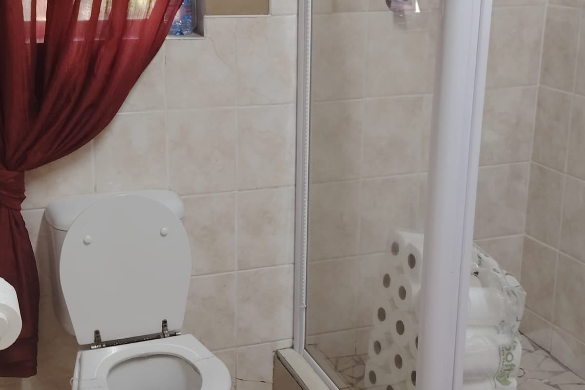 A functional bathroom featuring a standard toilet and a glass-enclosed shower with neutral ceramic tiling.