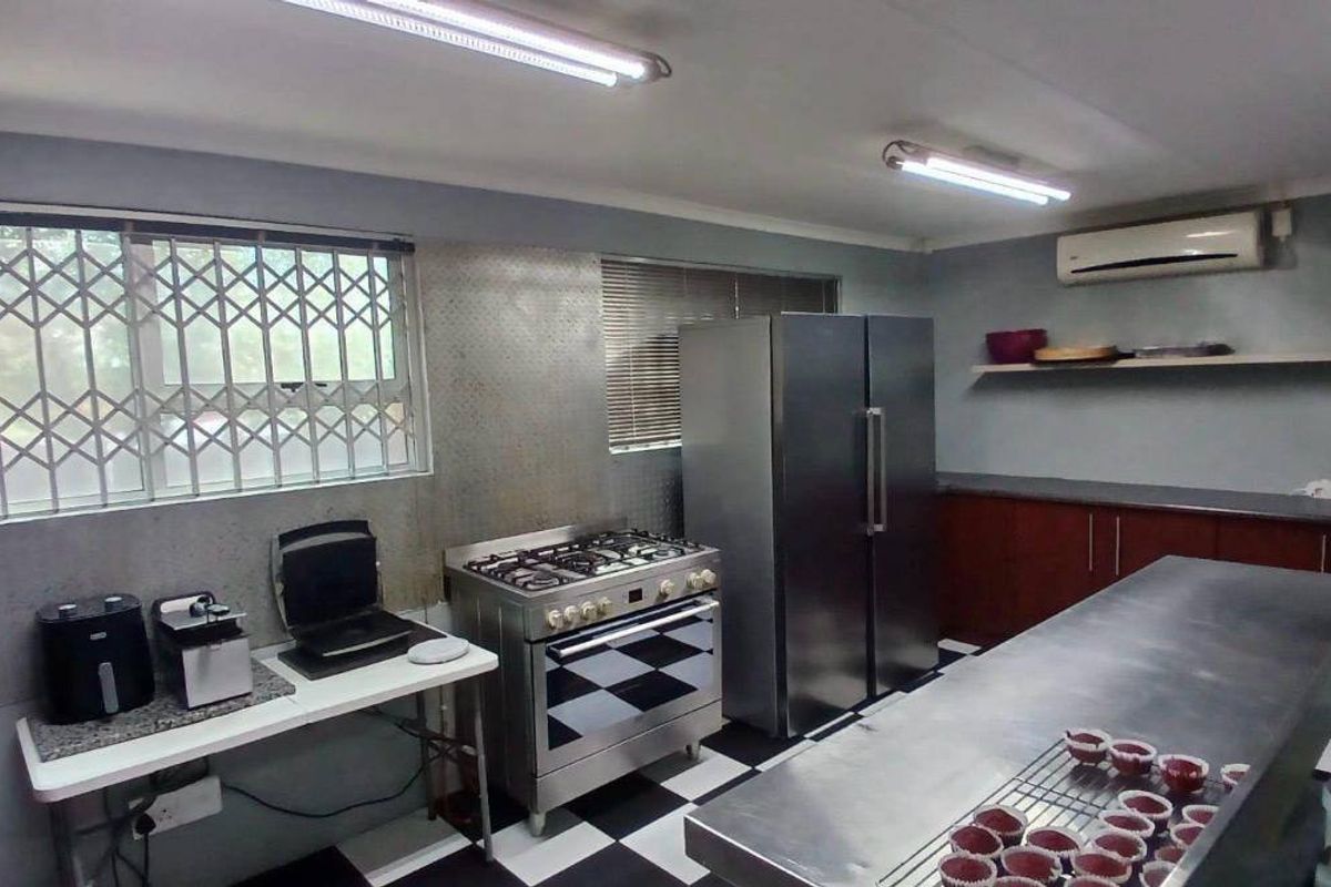 Commercial kitchen space featuring a gas stove, stainless steel prep surfaces, built-in cabinetry, and split system air conditioning.