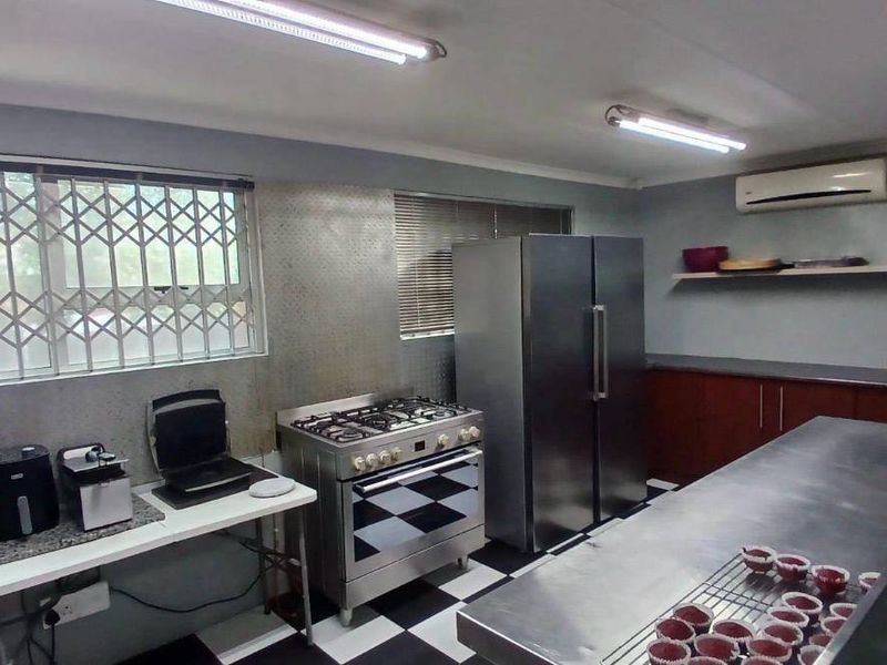 Commercial kitchen space featuring a gas stove, stainless steel prep surfaces, built-in cabinetry, and split system air conditioning.
