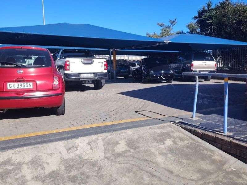 Commercial parking area featuring a paved driveway with shade cloth carports and a concrete access ramp.