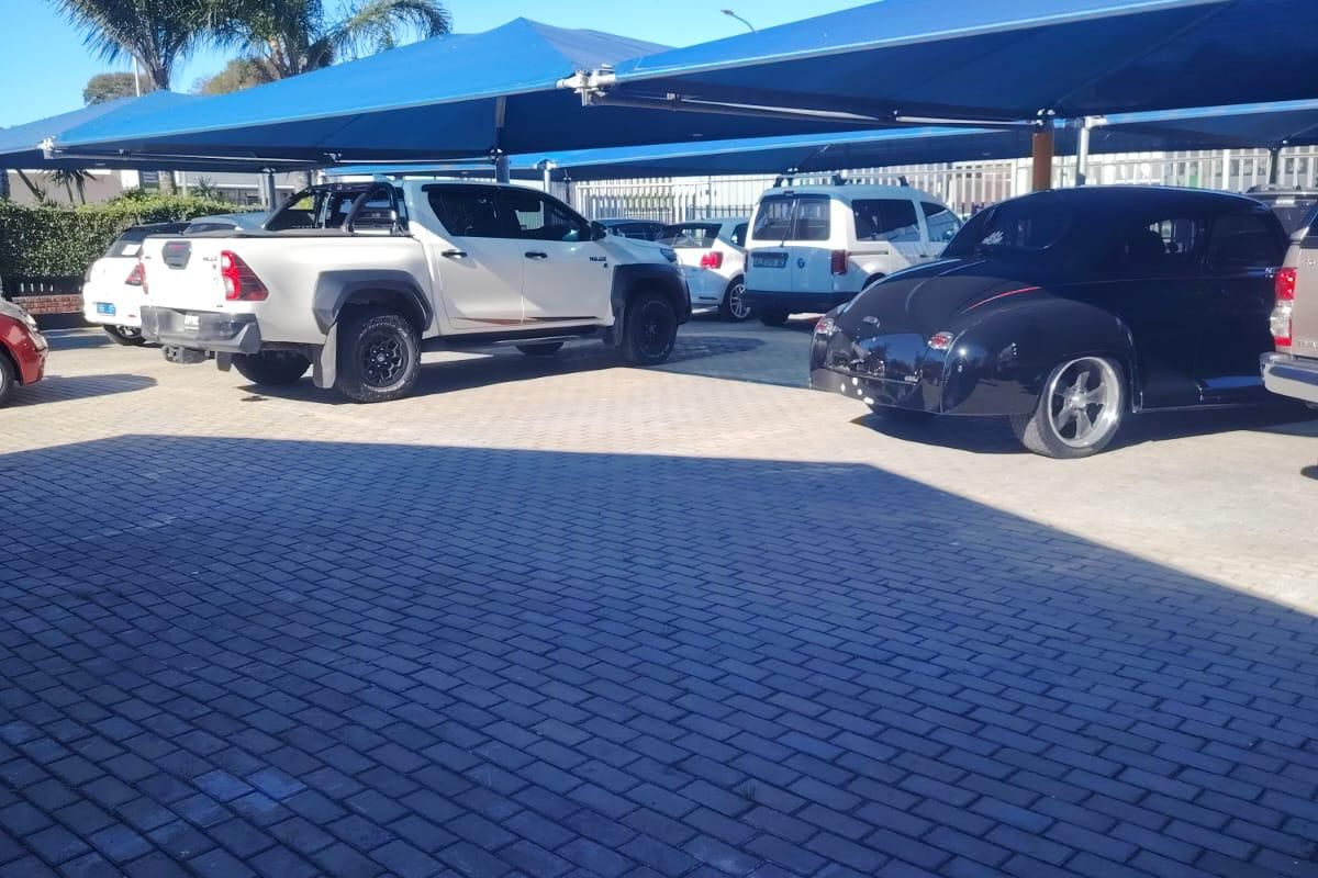 Commercial parking area featuring a paved surface and blue shade cloth carport structures for vehicle protection.