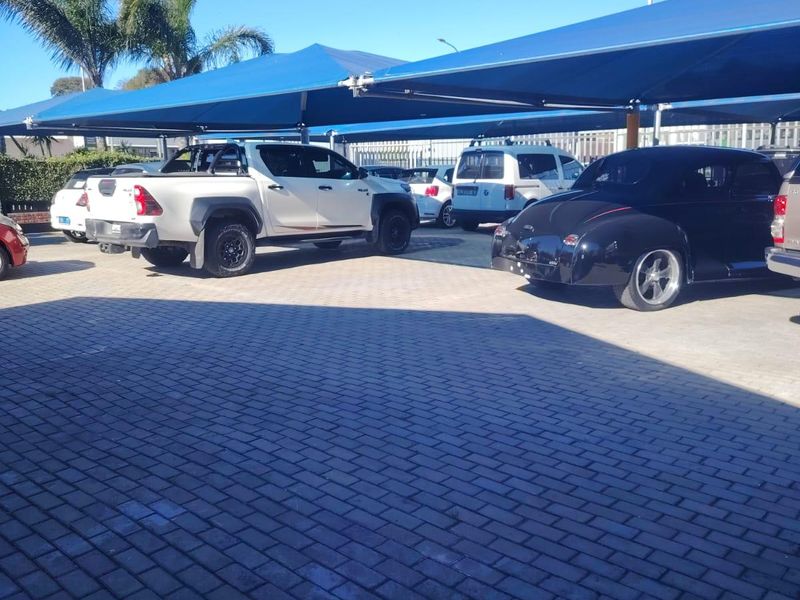 Commercial parking area featuring a paved surface and blue shade cloth carport structures for vehicle protection.