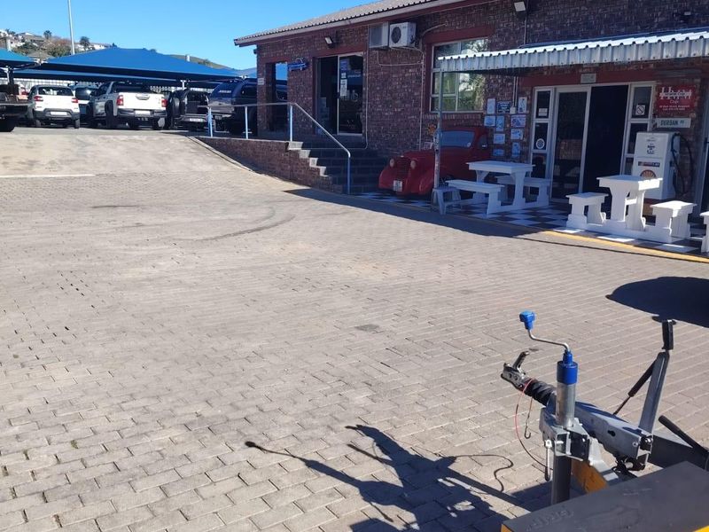 Commercial property exterior featuring a paved driveway, brick facade, and covered parking area with an attached metal awning.