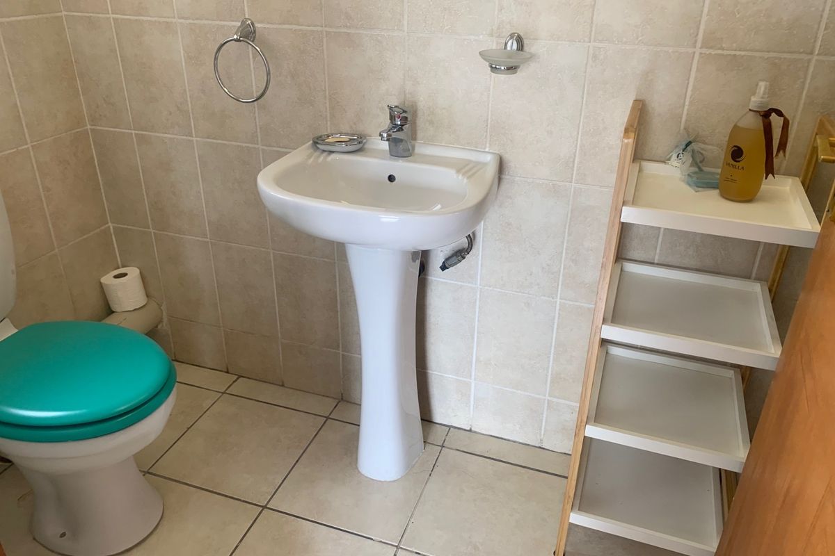 A functional guest bathroom featuring a pedestal basin, toilet, and neutral wall and floor tiling.