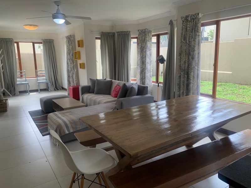 Spacious open-plan living and dining area featuring tiled flooring, ceiling fan, and large sliding glass doors providing natural light and garden access.