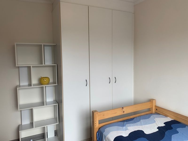 A bedroom featuring white built-in cupboards providing ample storage space.