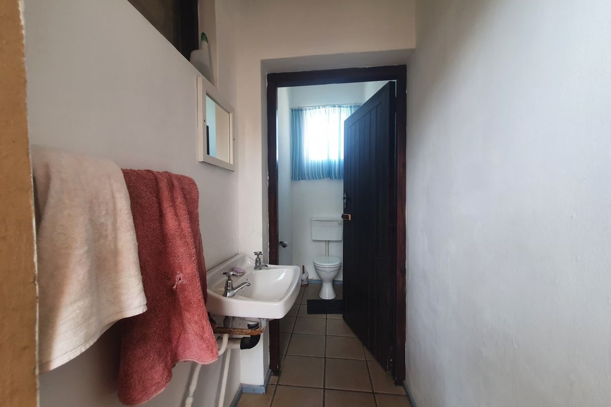 A functional bathroom featuring a wall-mounted basin and a separate toilet area with tiled flooring.